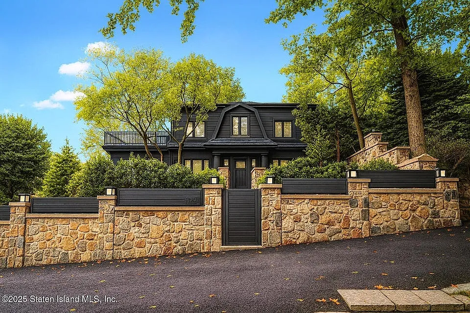 Custom black mansion with hand-laid stone perimeter wall by VIK MGM